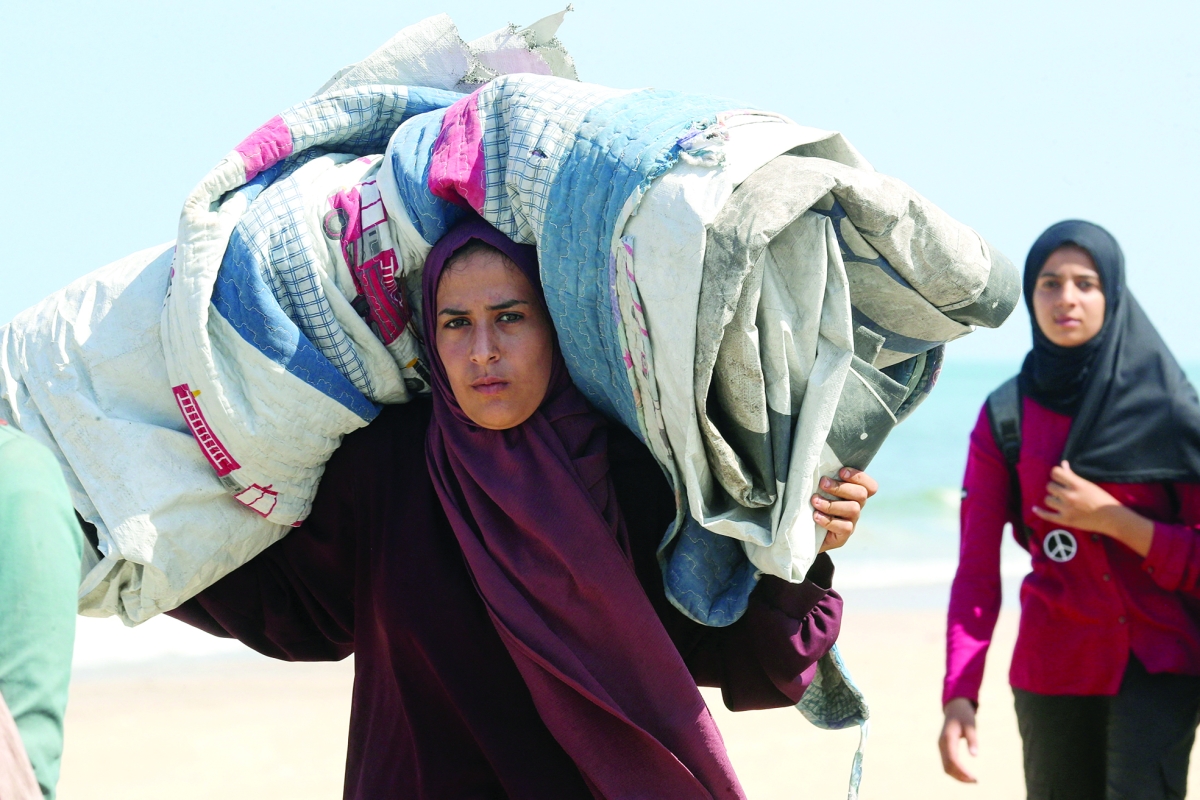 نازحة تحمل أمتعتها خلال فرارها من الغارات الإسرائيلية المتواصلة على شمال غزة (رويترز)