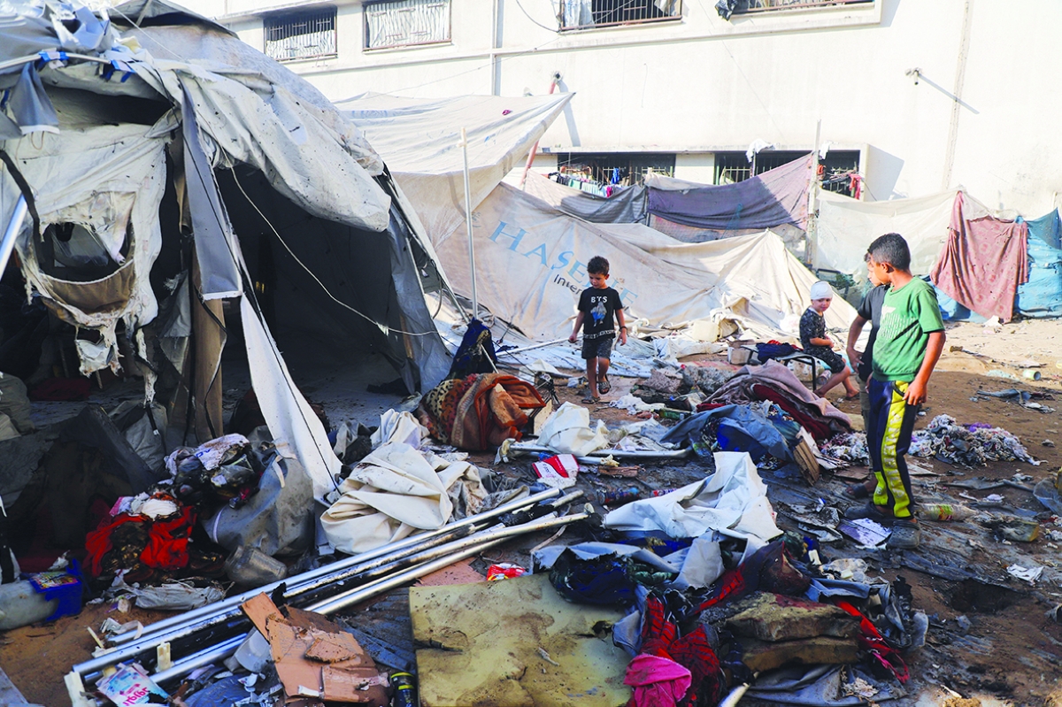 أطفال يتفقدون خيمة للنازحين قصفتها إسرائيل في غزة (رويترز)