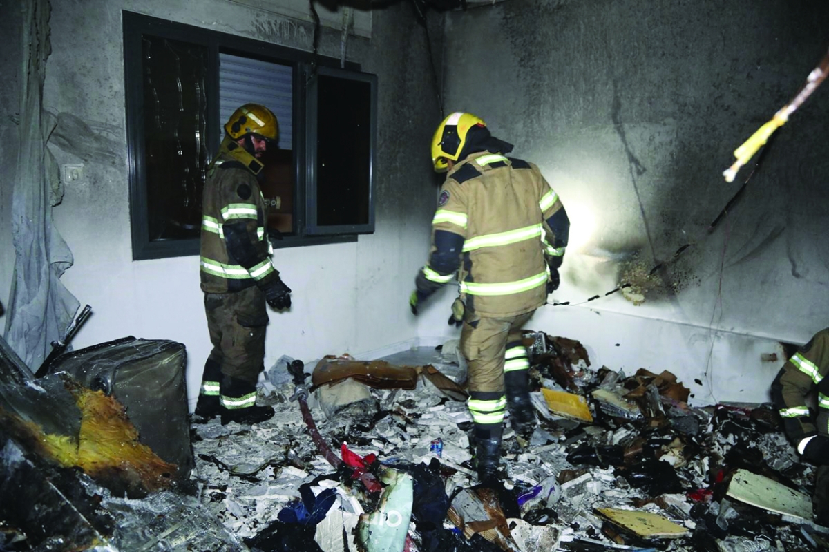 إطفائيان يعاينان موقع الحريق في المنصورية