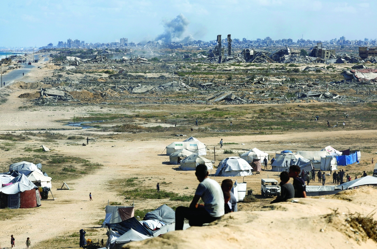 فلسطيني ينظر إلى دخان الغارات والدمار الواسع في غزة (رويترز)