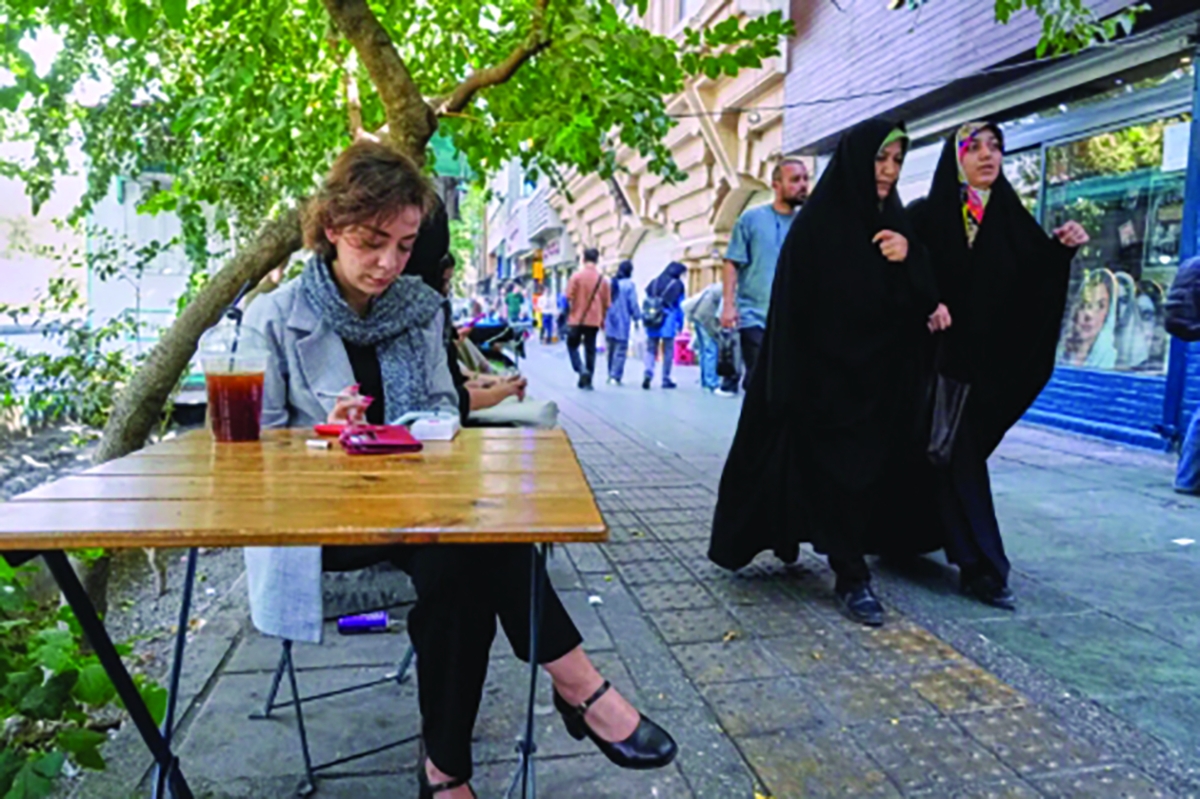 امرأة تجلس أمام أحد المقاهي في شارع انقلاب (الثورة) وسط طهران 
