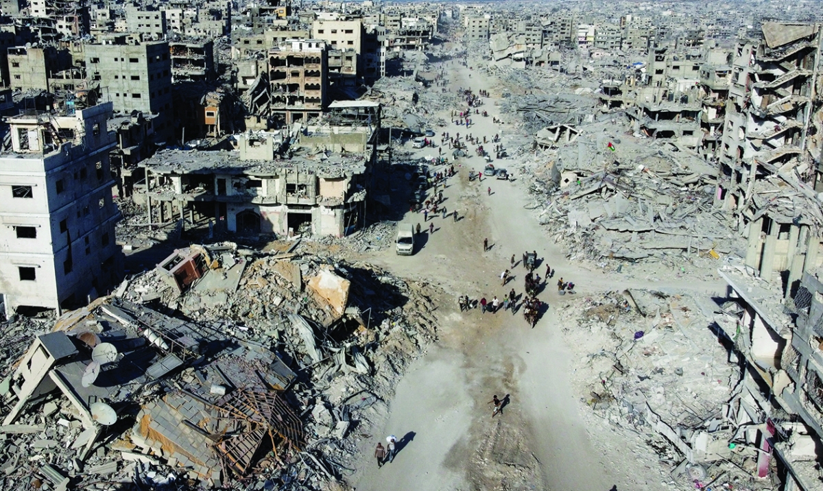 فلسطينيون يسيرون بين الأنقاض بعد انسحاب القوات الإسرائيلية في غزة (رويترز)