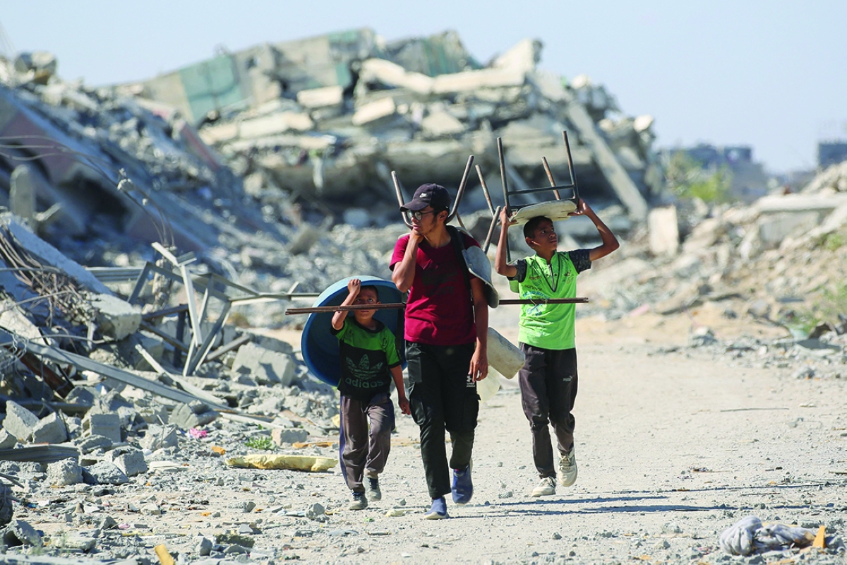 فلسطينيون يسيرون وسط الركام في مخيم النصيرات للاجئين (أ ف ب)