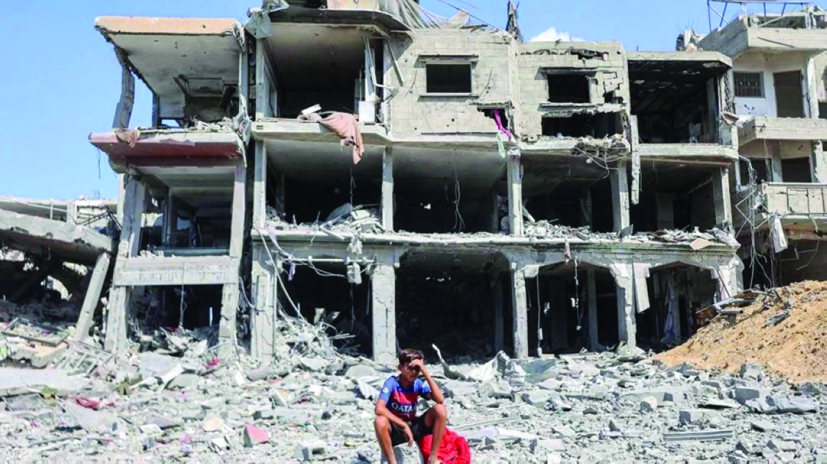 طفل فلسطيني يجلس أمام مبنى مُدمر في غزة