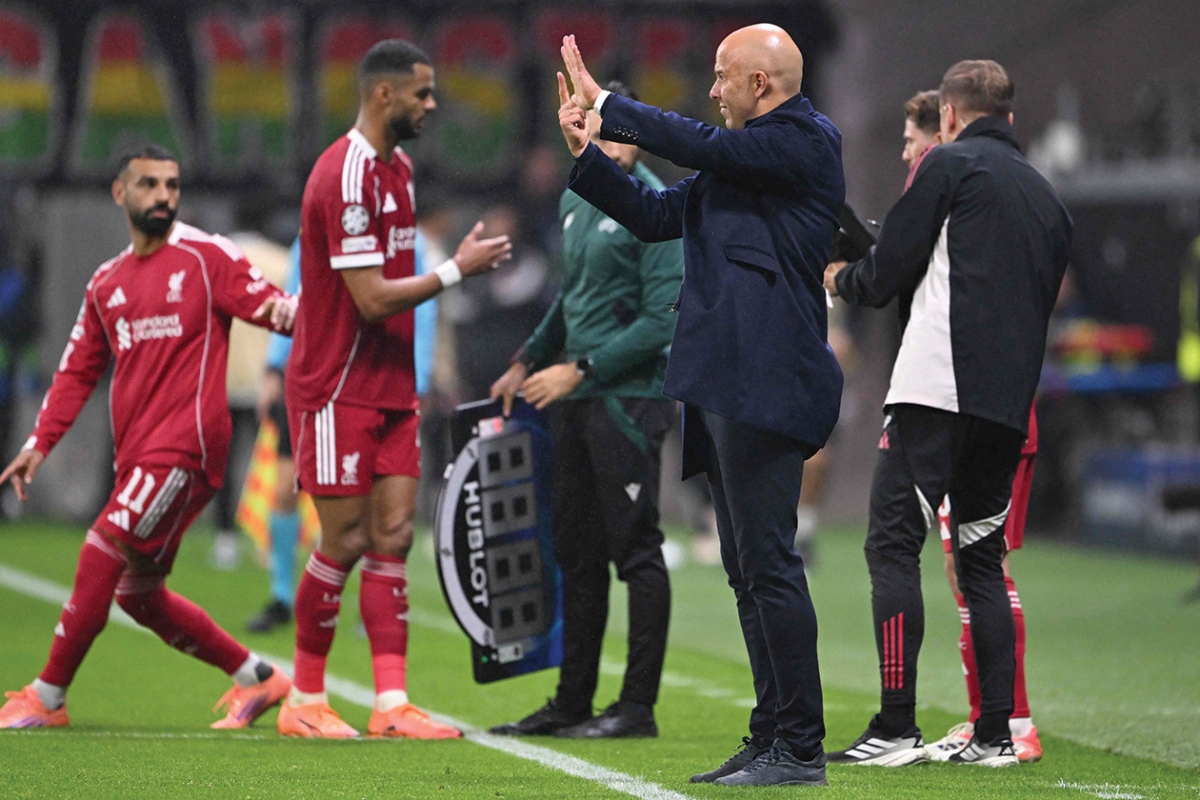 محمد صلاح يهم بدخول الملعب كبديل في مباراة ليفربول وآينتراخت فرانكفورت تحت أنظار مدربه سلوت (أ ف ب) 