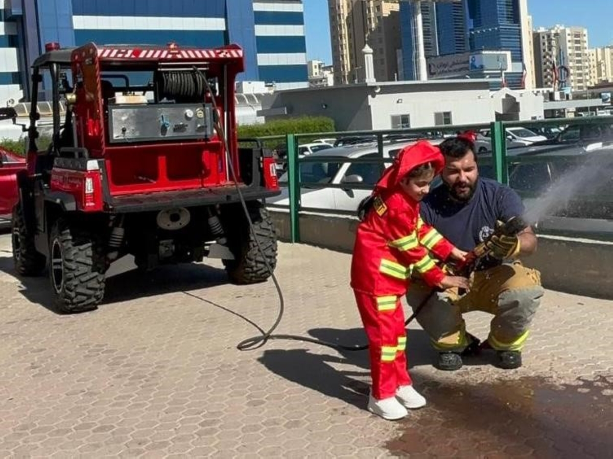 إطفائي يدرب طفلة على سبل الوقاية من الحريق