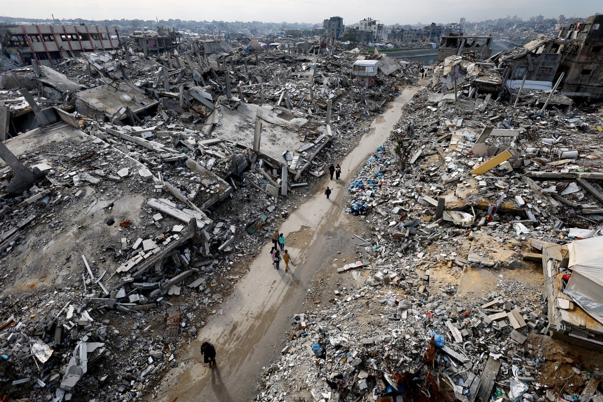 فلسطينيون يسيرون وسط الركام في مخيم جباليا للاجئين (رويترز)