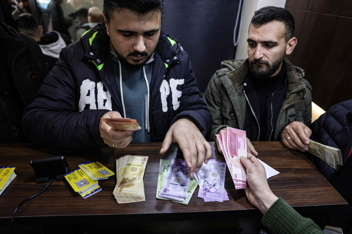 سوريان يستبدلان العملة القديمة في أحد مصارف دمشق (أ ف ب)