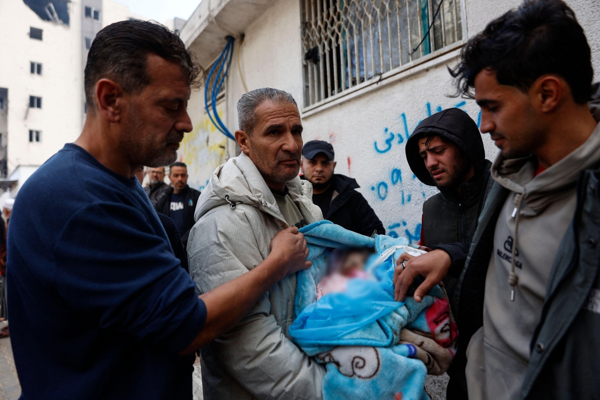فلسطيني يحمل طفلاً رضيعاً استشهد في الغارات الإسرائيلية على غزة (أ ف ب) 