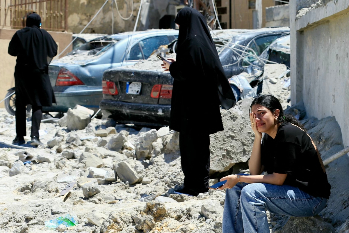فتاة تبكي وهي جالسة على الأنقاض في موقع غارة إسرائيلية استهدفت بلدة قناريت (أ ف ب)