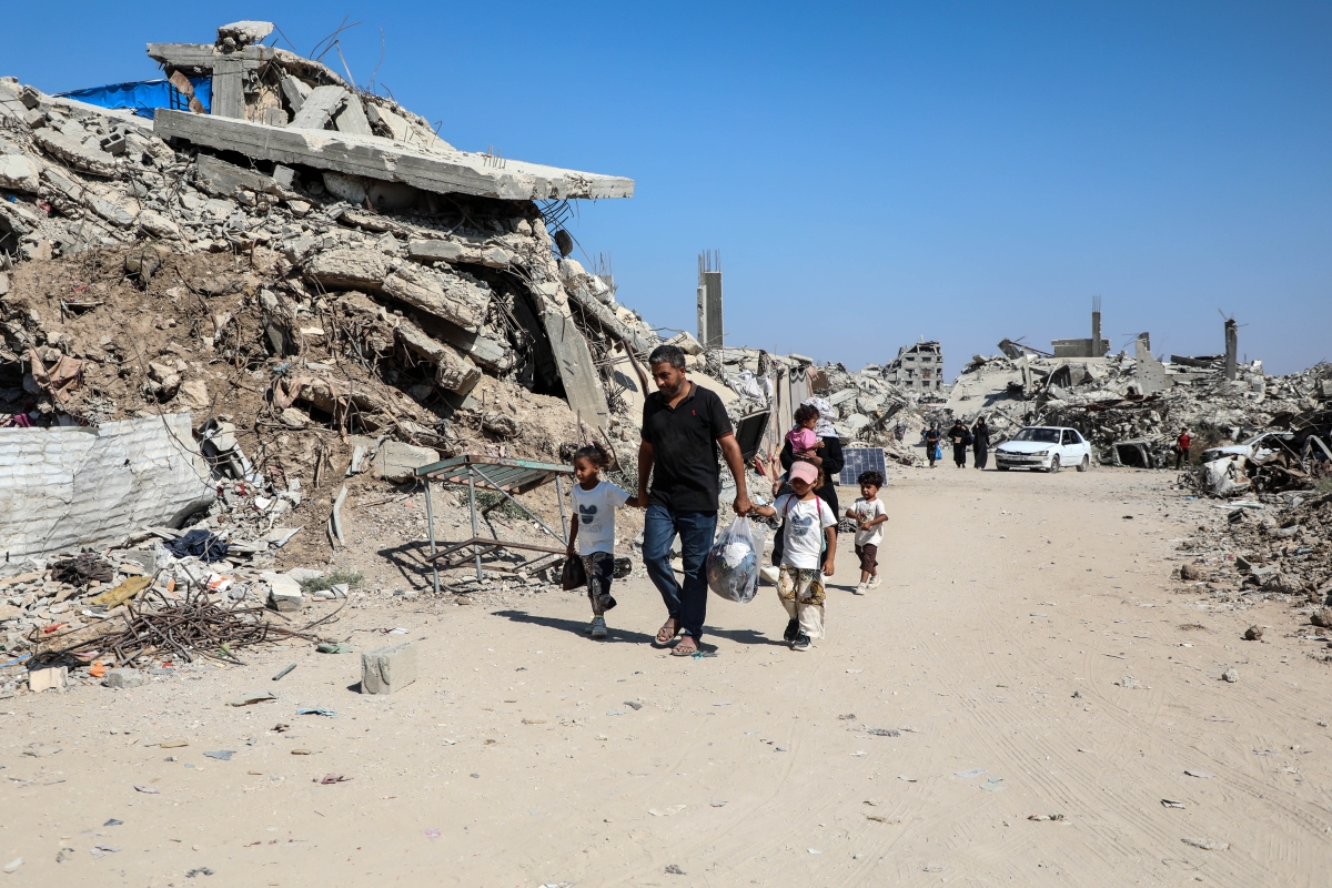 فلسطينيون يسيرون وسط الركام في حي الزيتون جنوب شرقي غزة  (أ ف ب)